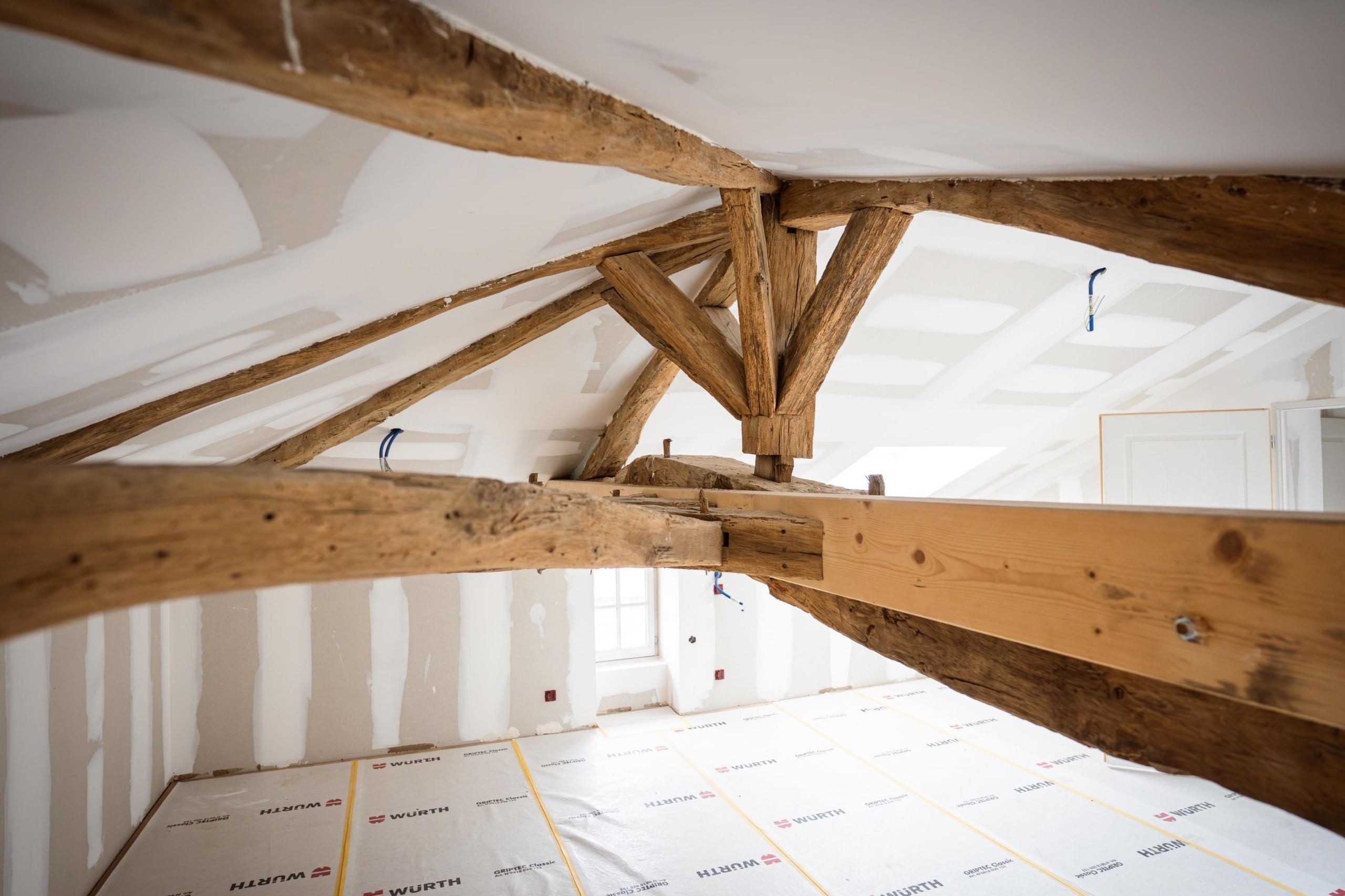 Vieilles poutres en bois dans un grenier rénové.
