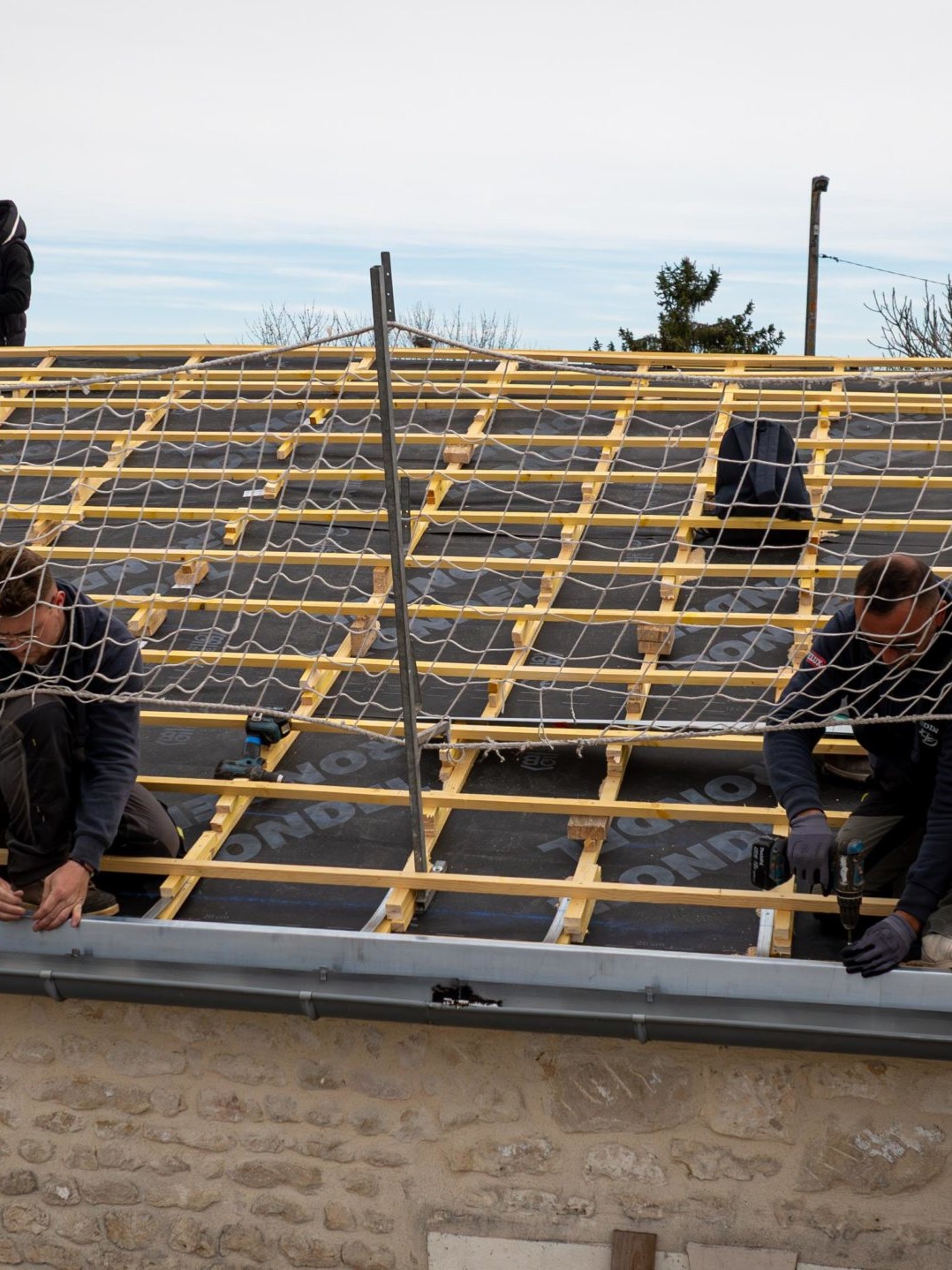 Travailleurs sur un toit en construction avec filet.