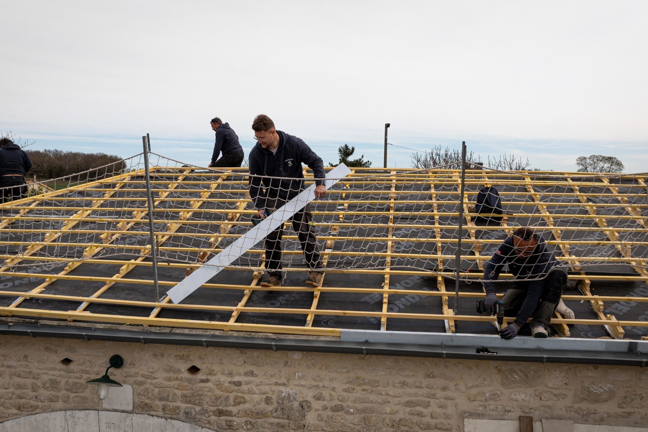 Travailleurs installant un filet de sécurité sur un toit.