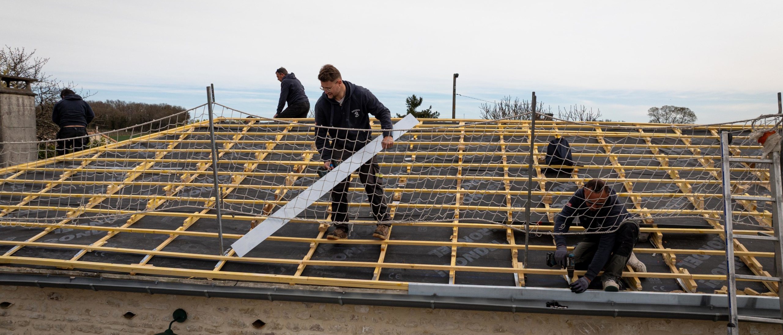 Travailleurs installant un filet de sécurité sur un toit.