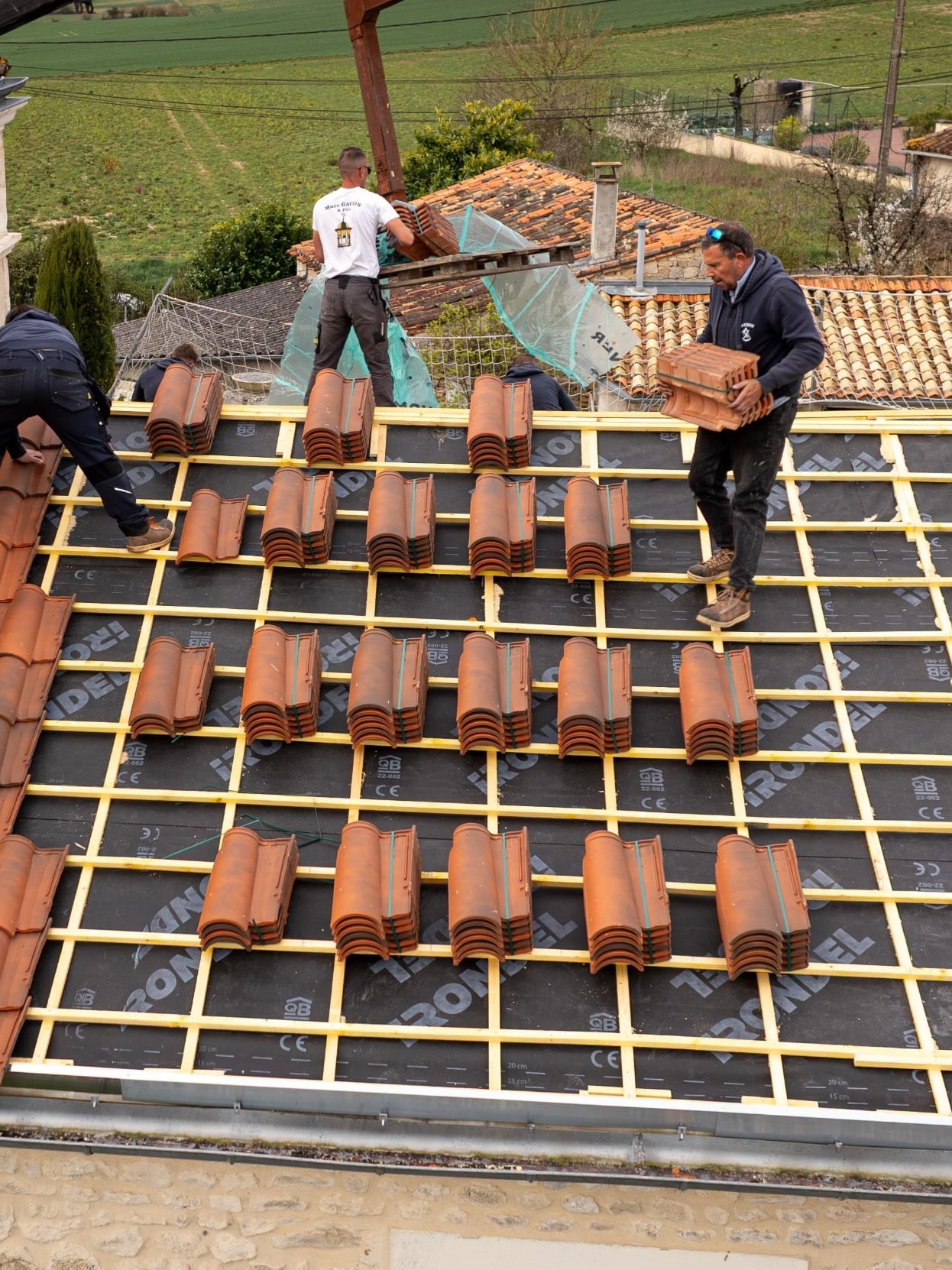 Ouvriers posant des tuiles sur un toit.