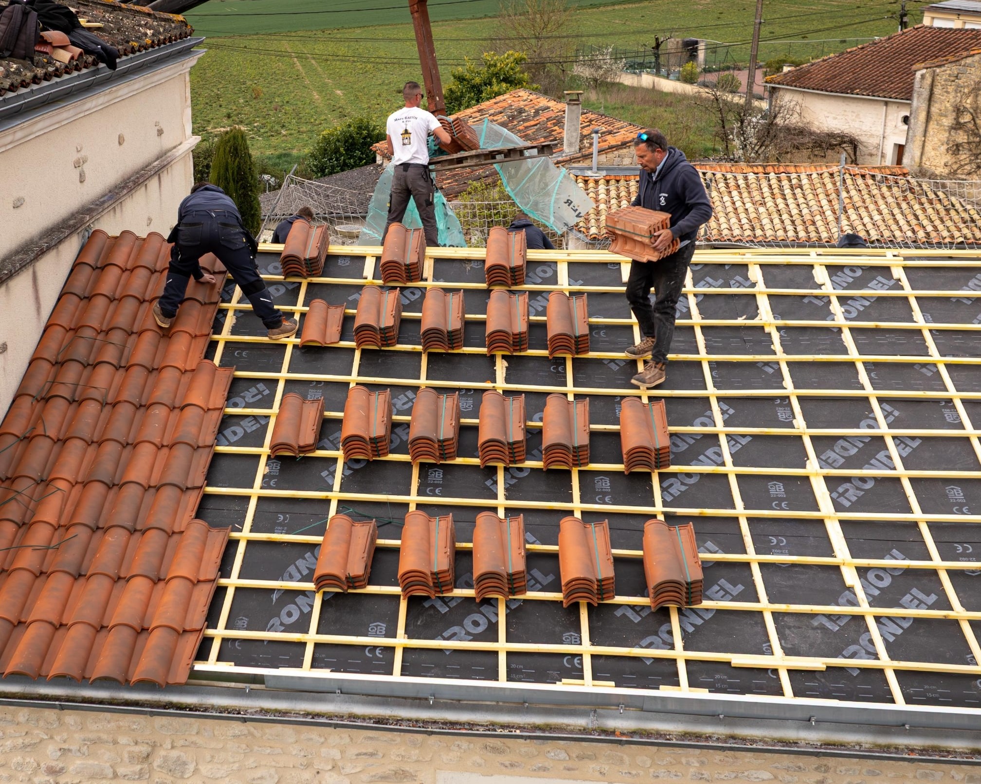 Ouvriers posant des tuiles sur un toit.