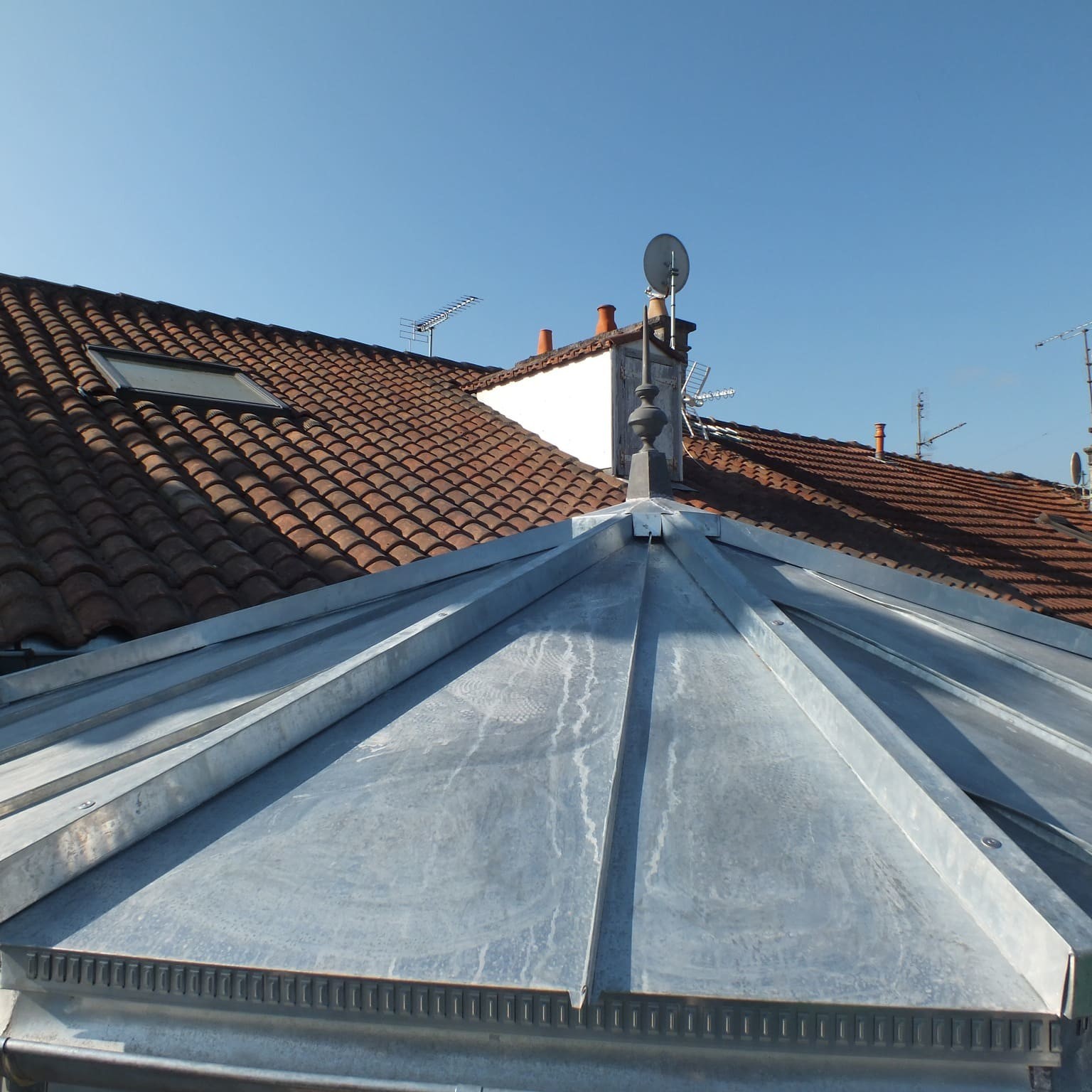 Toits rouges et antennes sous ciel bleu en France.